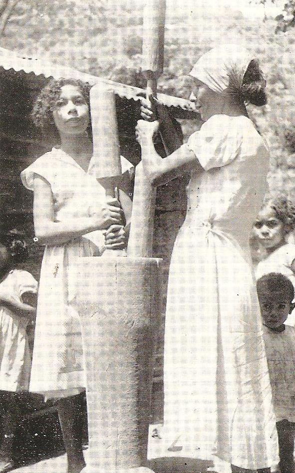 Two women make arepa dough with a pilon